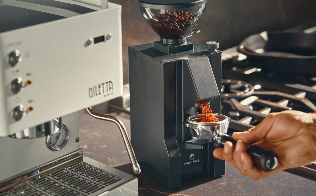 Electric espresso grinder dispensing fresh grounds into a portafilter beside a Diletta Mio espresso machine