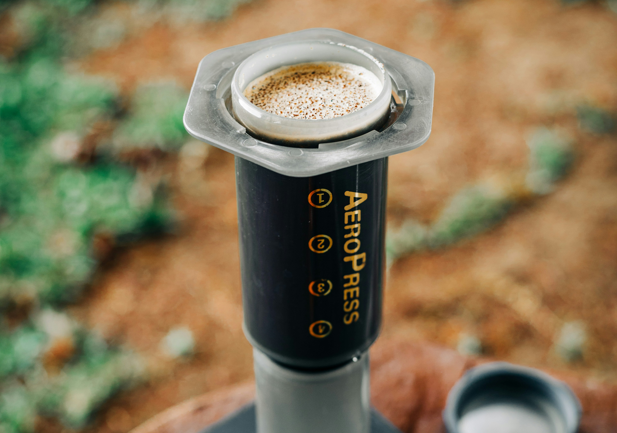 AeroPress coffee maker brewing outdoors with coffee grounds in the filter cap, perfect for portable coffee on the go - Seattle Coffee Gear