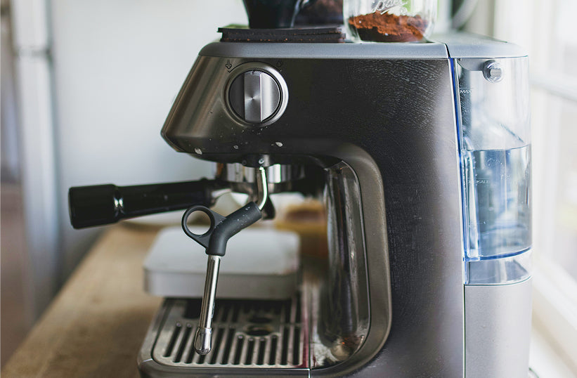 A home espresso machine with a visible water reservoir and steam wand