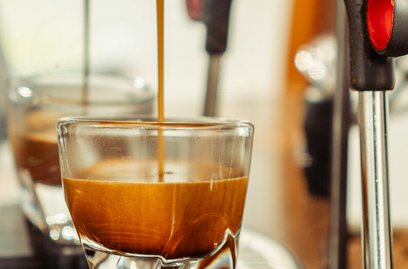 A close-up of a double espresso shot extracting into a clear glass