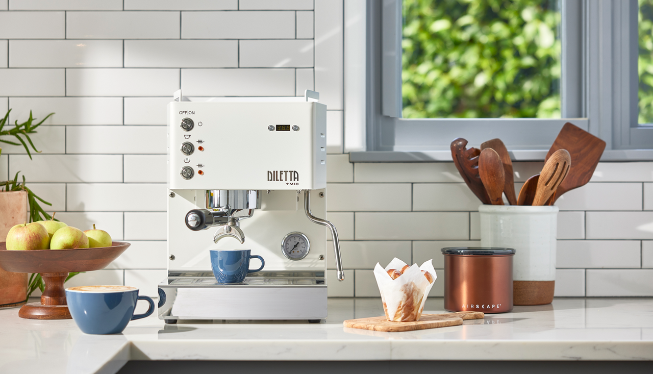 Diletta Mio sits on a kitchen counter with freshly made espresso and latte drinks.