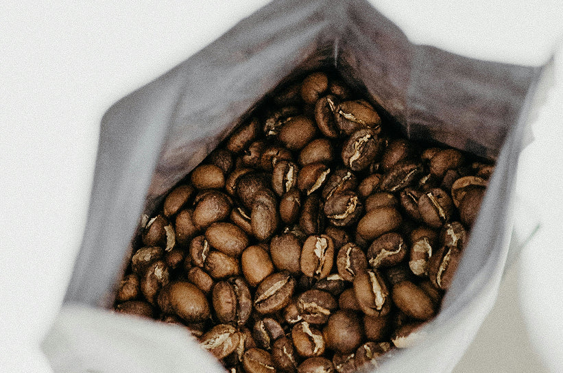 An open bag of light roast whole coffee beans viewed from above
