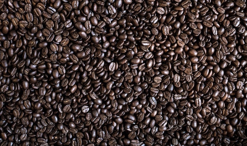A scattered collection of whole roasted coffee beans photographed up close