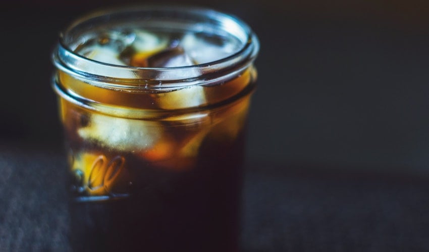 A glass jar filled with iced coffee on a dark background - Seattle Coffee Gear