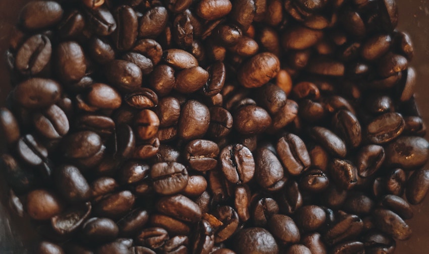 A close-up pile of roasted coffee beans spread across a dark background