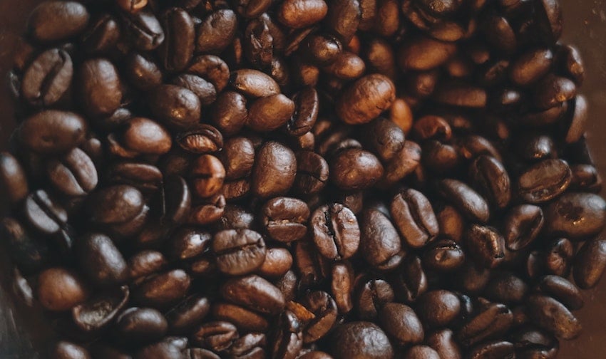 A close-up pile of roasted coffee beans spread across a dark background
