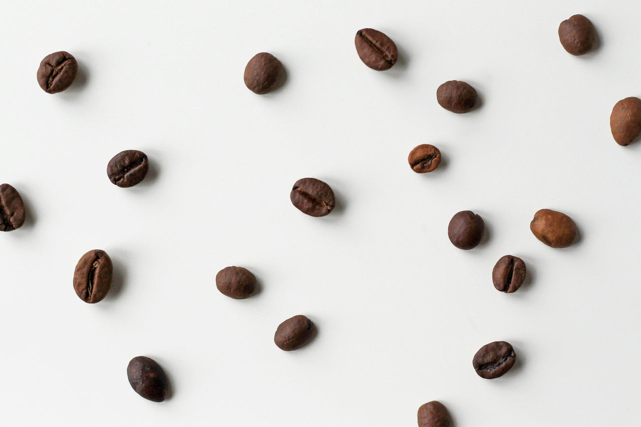 Coffee beans on a white backgroumd - by Nordwood Themes via Unsplash