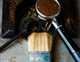 Espresso machine cleaning tools including a group head brush, portafilter with coffee grounds, and a knock box on a countertop