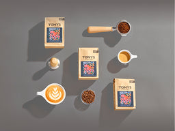 A selection of Tony's Coffee products on a dark gray background with portafilter and latte's. 