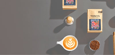 Tony's coffee products including coffee beans, packaging, and a cup of coffee on a dark surface.